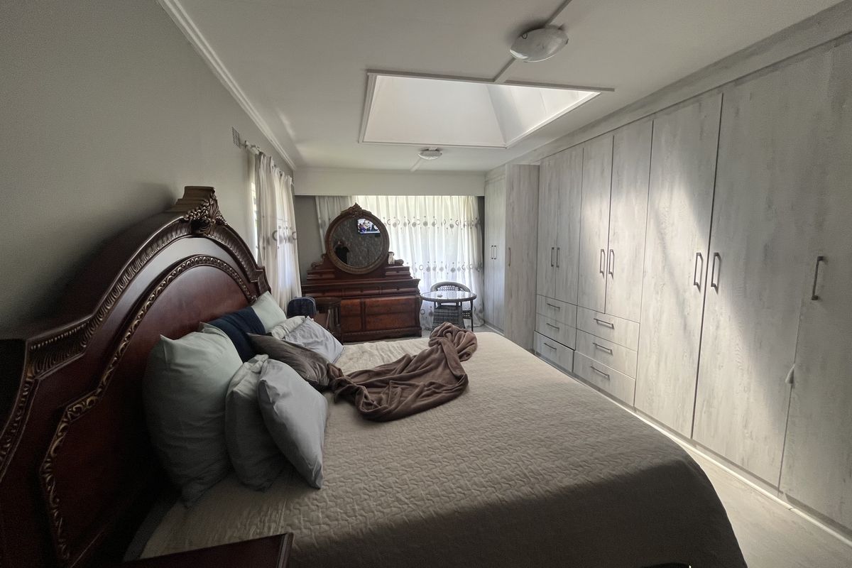 Spacious bedroom featuring extensive built-in cupboards, a central skylight, and neutral finishes, offering ample storage and natural light.