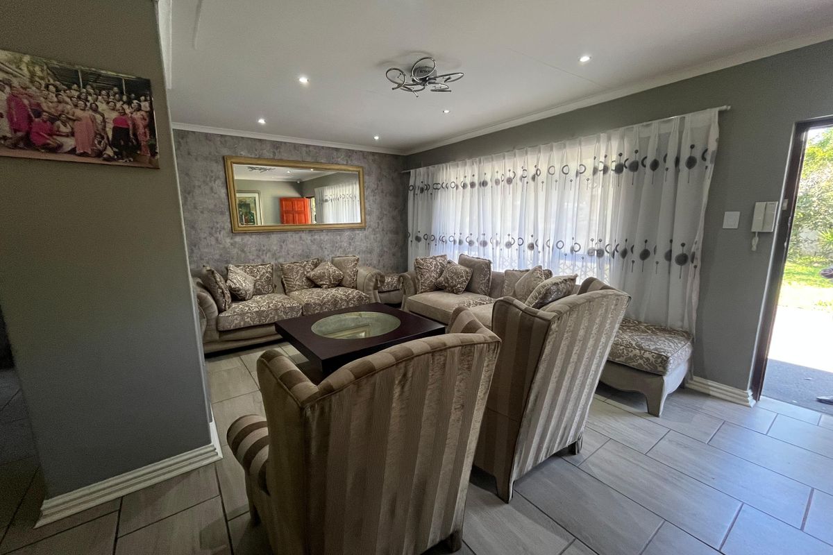 A well-maintained living room featuring neutral tiled flooring, recessed downlighting, and a sliding glass door providing access to the exterior.