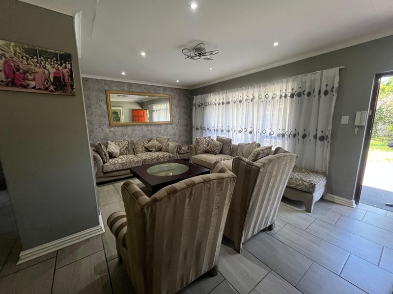 A well-maintained living room featuring neutral tiled flooring, recessed downlighting, and a sliding glass door providing access to the exterior.