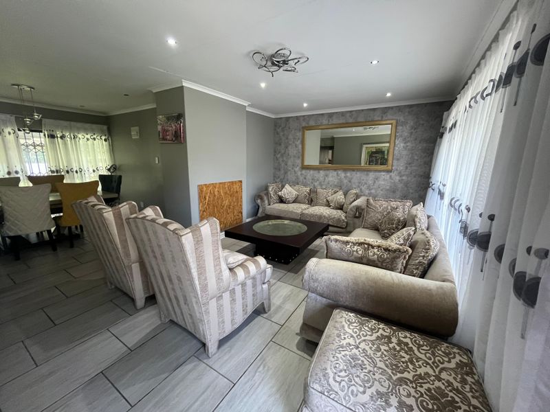 Spacious open-plan living area featuring modern tiled flooring, recessed downlighting, and a feature wall with a built-in fireplace.