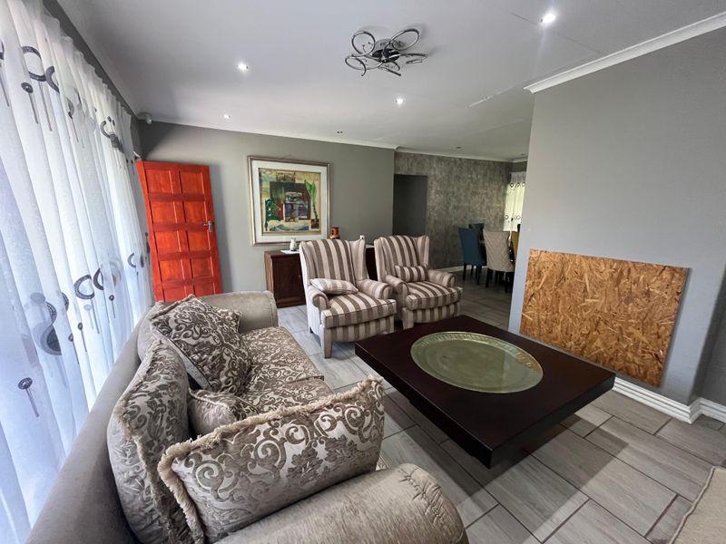 Open-plan living and dining area featuring tiled floors, recessed lighting, and a feature wall, with an unfinished fireplace area requiring attention.