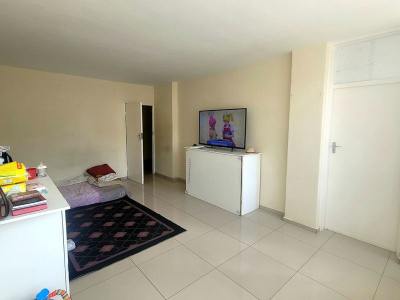 A living room area featuring neutral tiled flooring and standard internal doors, providing a functional and versatile space for relaxation.