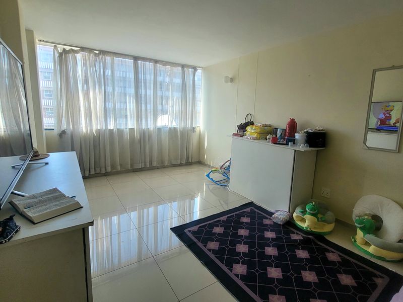 A living room featuring large windows with natural light and tiled flooring throughout.