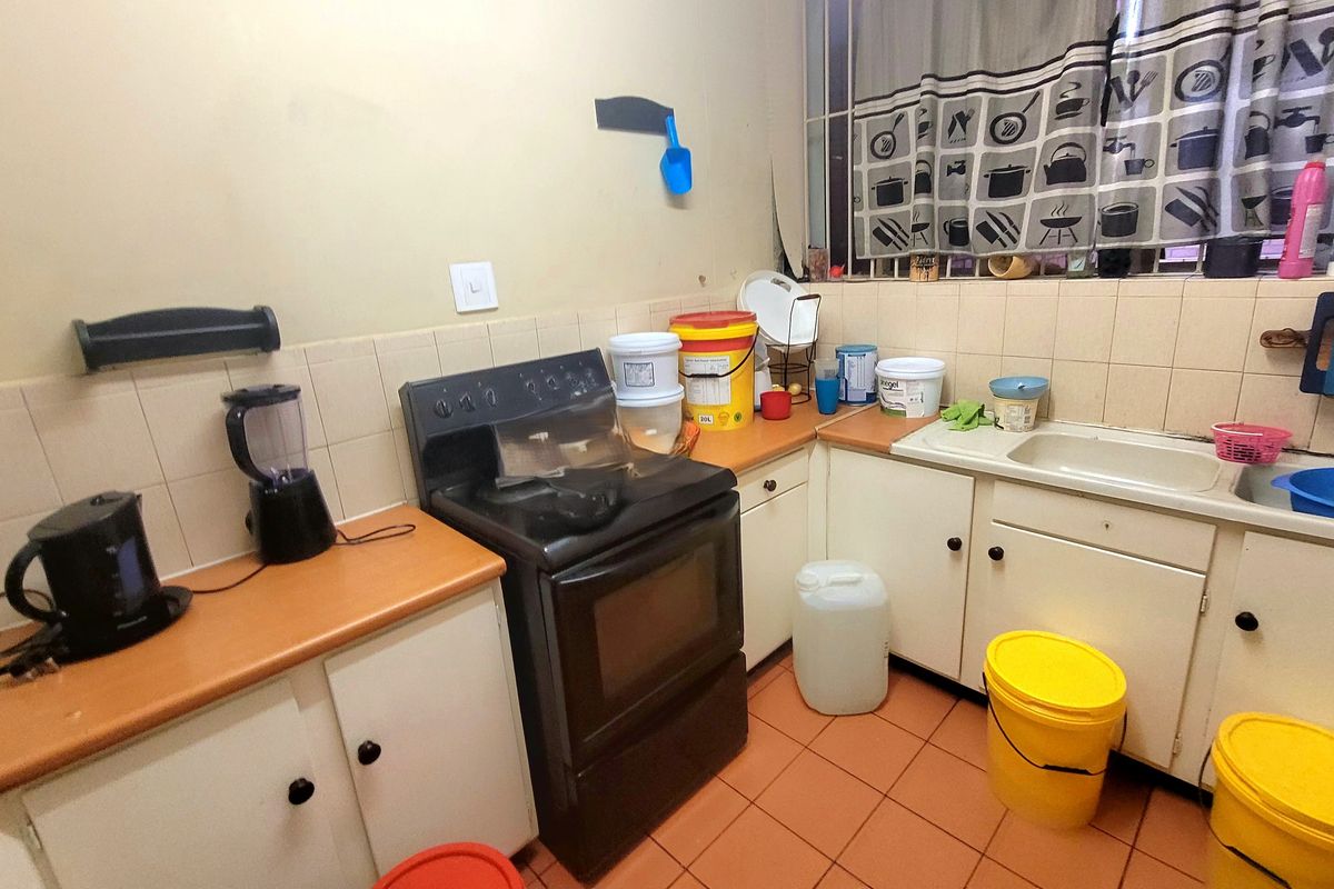 A functional kitchen featuring built-in cabinetry, laminate countertops, a freestanding stove, and tiled flooring, offering a practical layout for daily meal preparation.