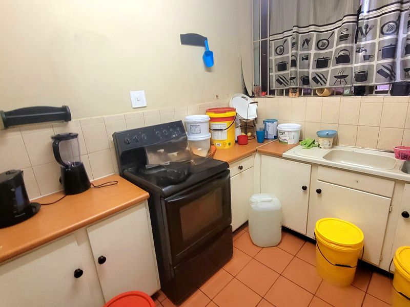 A functional kitchen featuring built-in cabinetry, laminate countertops, a freestanding stove, and tiled flooring, offering a practical layout for daily meal preparation.
