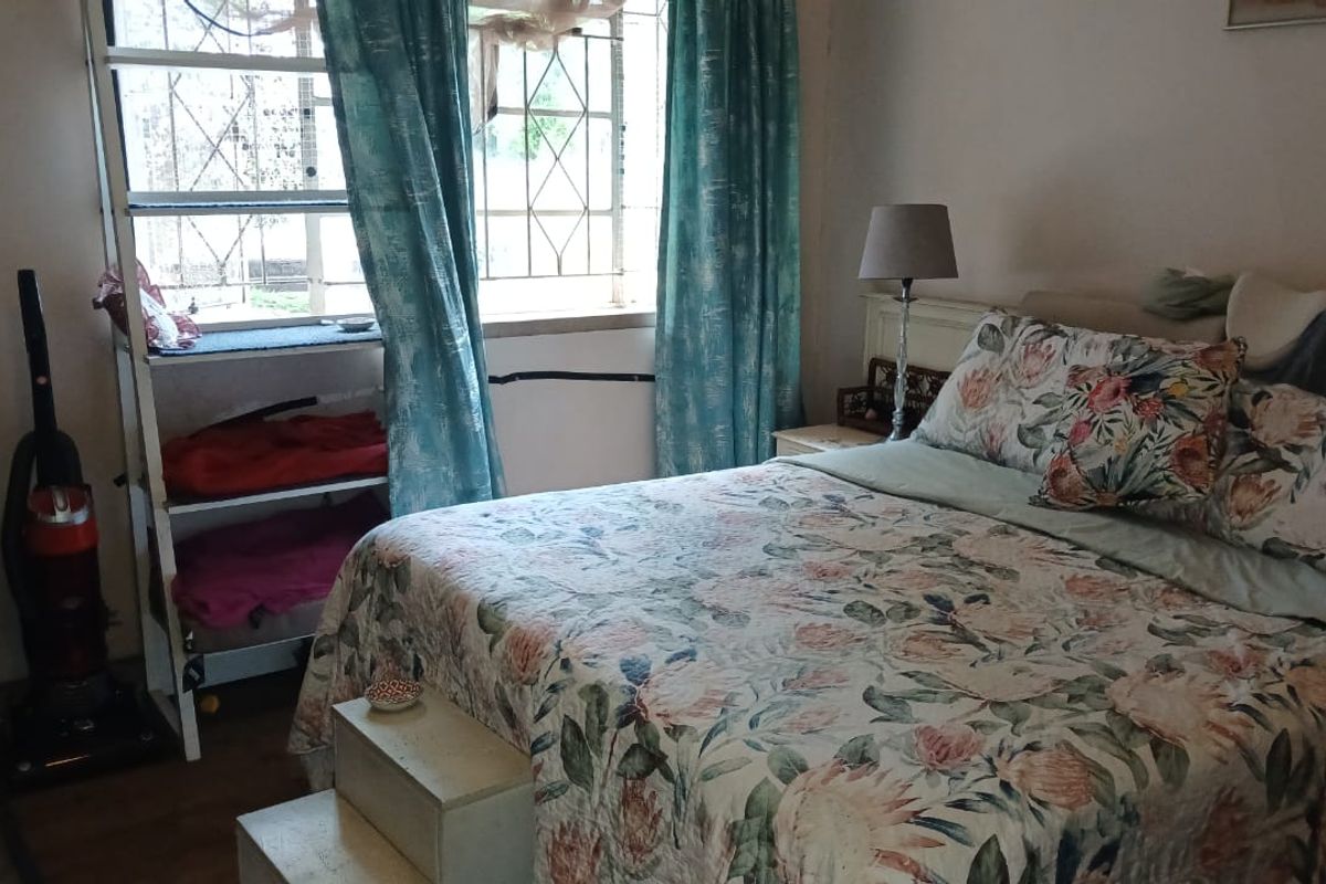 A bedroom featuring laminate flooring and a window with a security gate, requiring cosmetic updates to improve its overall condition and appeal.
