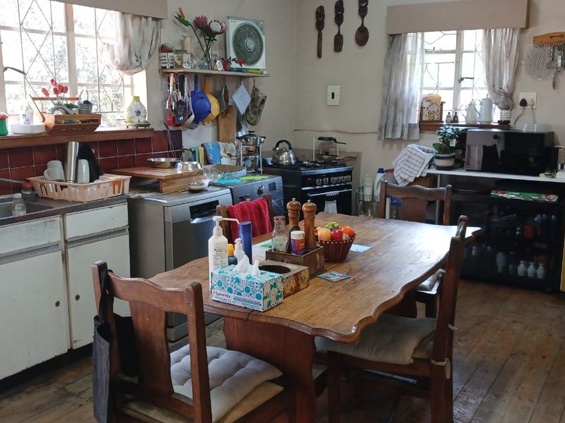 Open-plan kitchen and dining area featuring timber flooring, dated cabinetry, and a tiled backsplash, offering significant potential for a modern renovation.