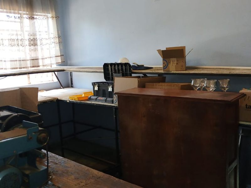 A functional utility or workshop space featuring a built-in workbench and window with security bars, suitable for storage or hobby use.