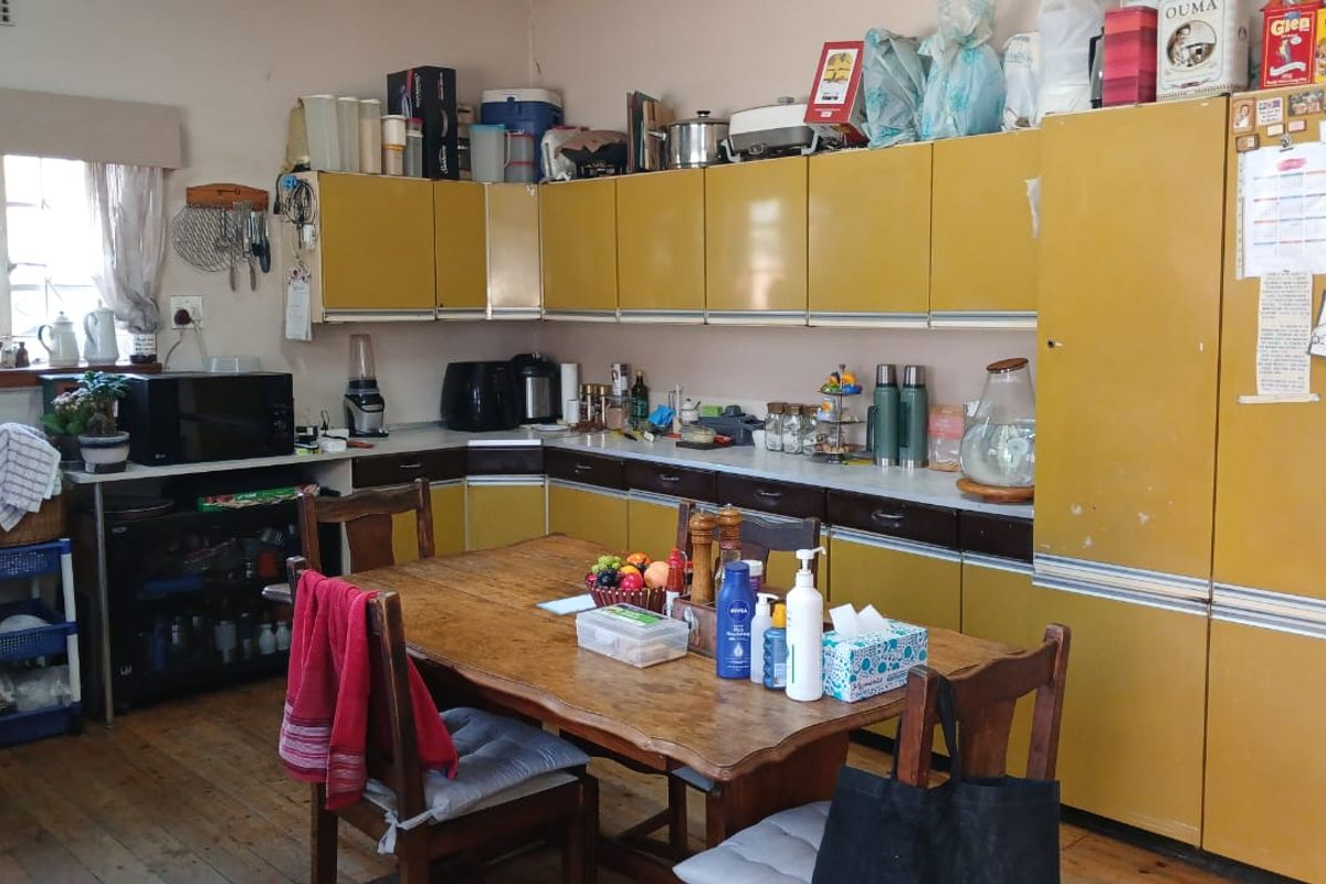 A dated kitchen featuring original yellow laminate cabinetry, laminate countertops, and timber flooring, offering significant potential for a modern renovation.
