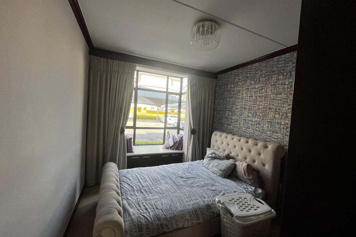 A cozy bedroom featuring a built-in window seat, a textured feature wall, and a central ceiling light fixture.