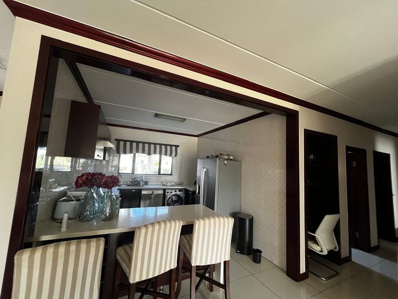 Open plan kitchen area featuring a breakfast bar, tiled flooring, and built-in cabinetry, seamlessly connecting to the adjacent living space.