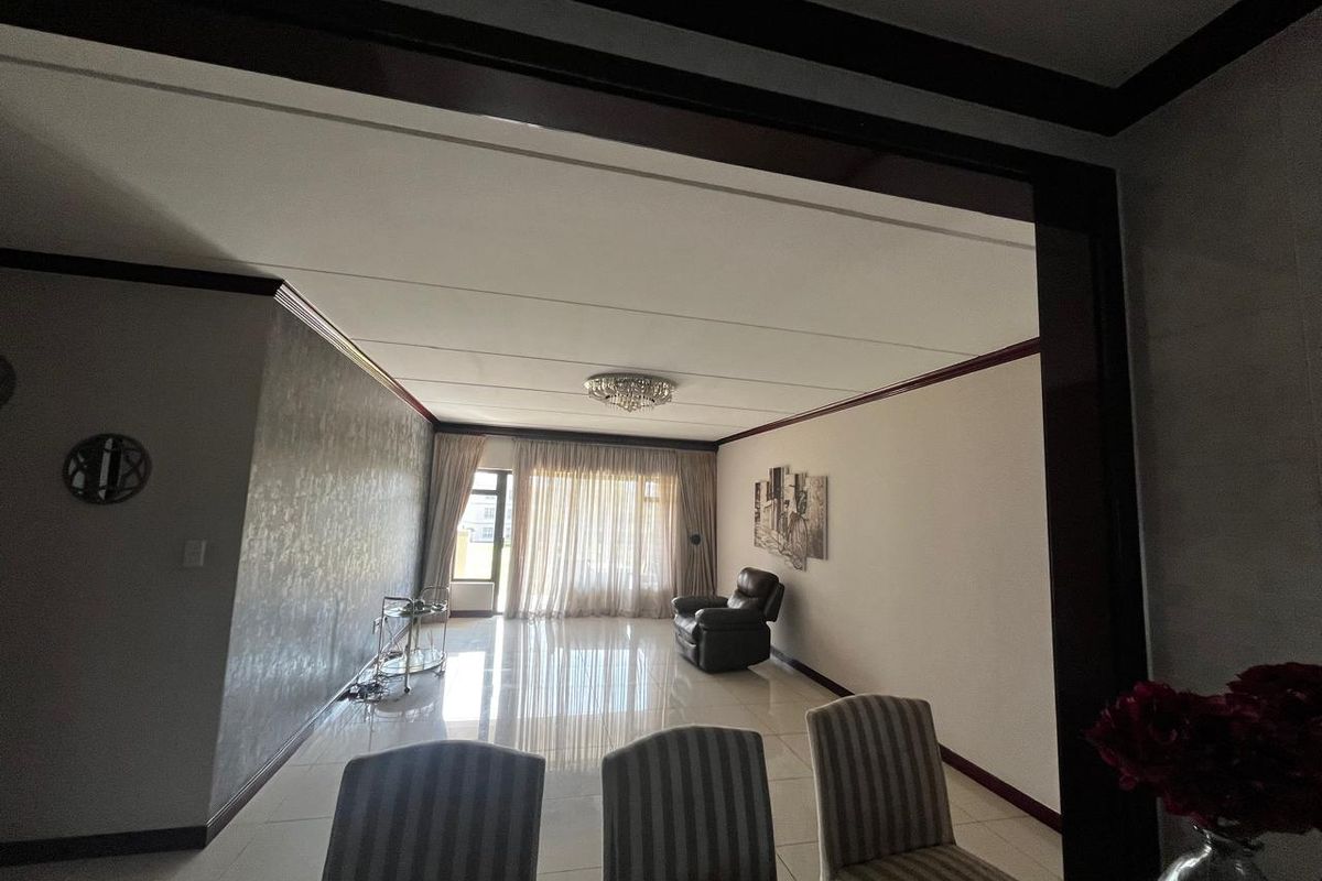 Spacious living area featuring polished tiled flooring, decorative ceiling moulding, and large sliding glass doors providing access to the exterior.