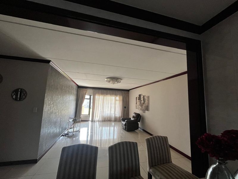Spacious living area featuring polished tiled flooring, decorative ceiling moulding, and large sliding glass doors providing access to the exterior.