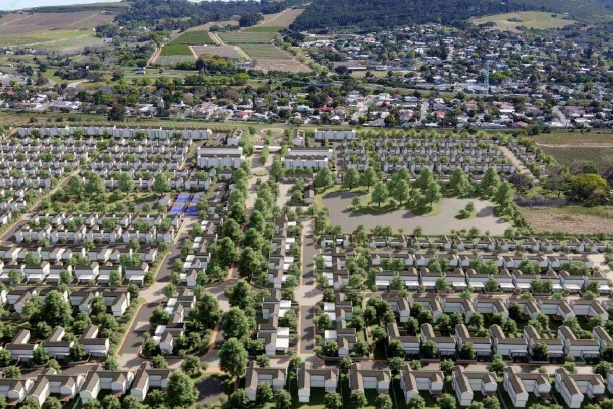An aerial perspective of a planned residential development featuring organized housing units, internal road infrastructure, and landscaped green areas with a central pond.