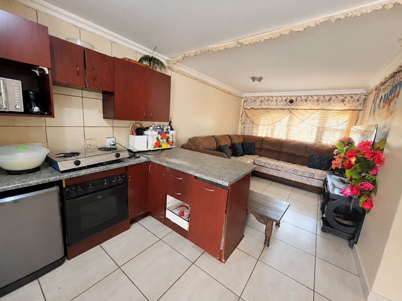 Open-plan living area featuring a kitchen with built-in cabinetry, granite countertops, and a gas hob, seamlessly flowing into the adjacent lounge space.