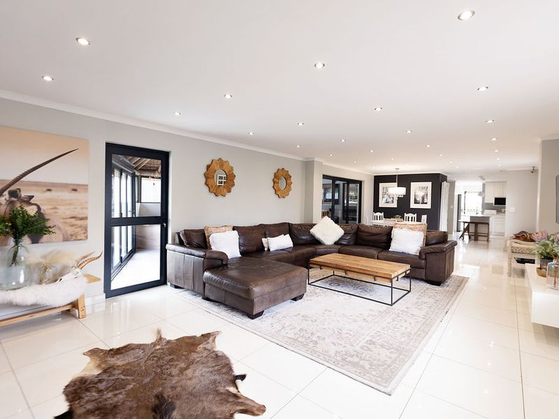 Spacious open-plan living area featuring polished tiled floors, recessed downlighting, and seamless flow to the dining and kitchen spaces.