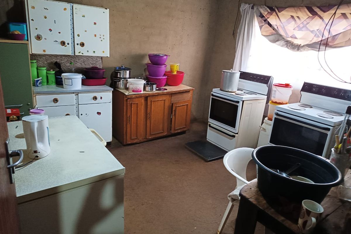 A dated kitchen area featuring basic cabinetry, multiple freestanding stoves, and unfinished wall surfaces, offering significant potential for renovation and modernization.