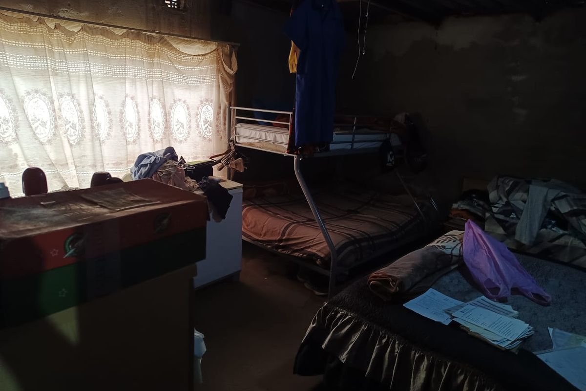 A bedroom featuring exposed roof structure and unfinished wall surfaces, requiring significant renovation to improve the living space.