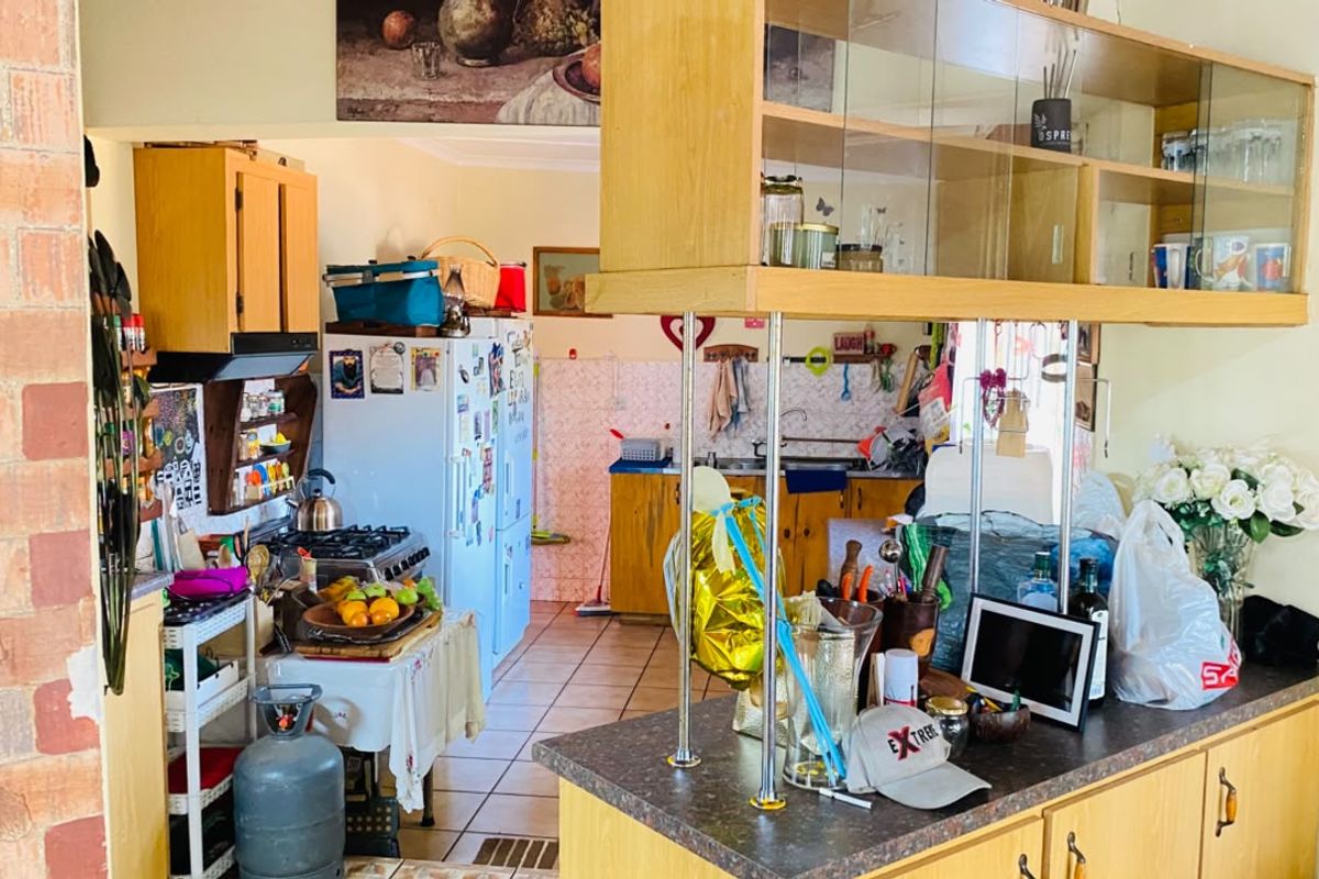 A functional kitchen featuring built-in wooden cabinetry, laminate countertops, a gas stove, and tiled flooring, offering potential for a modern renovation.