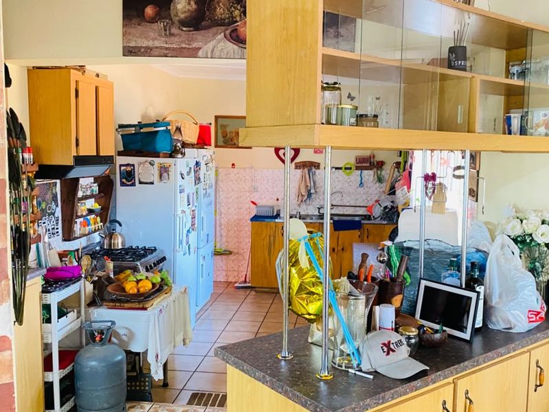A functional kitchen featuring built-in wooden cabinetry, laminate countertops, a gas stove, and tiled flooring, offering potential for a modern renovation.