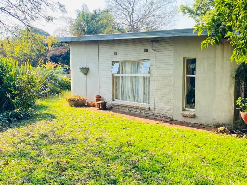 Rear view of the property showing a brick facade with aluminium window frames and a surrounding garden area.