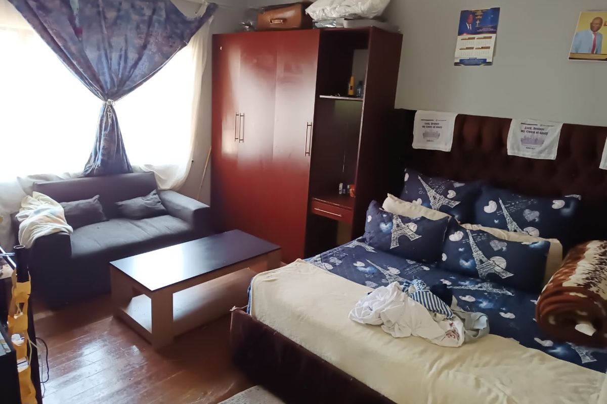 A bedroom featuring hardwood flooring and a built-in wardrobe, providing functional storage space within the room.