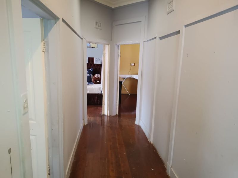 A functional hallway featuring original timber flooring and neutral wall finishes, providing access to multiple rooms within the home.