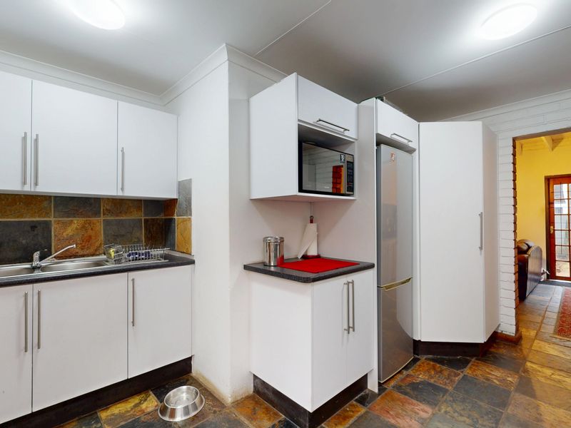 A functional kitchen featuring white cabinetry, slate tile flooring, and a matching slate backsplash, providing a practical workspace with integrated storage.