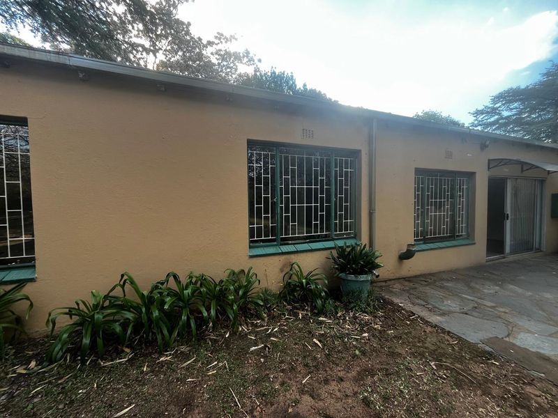 Rear exterior view of the cottage featuring stone patio, security-barred windows, and sliding door access to the garden area.