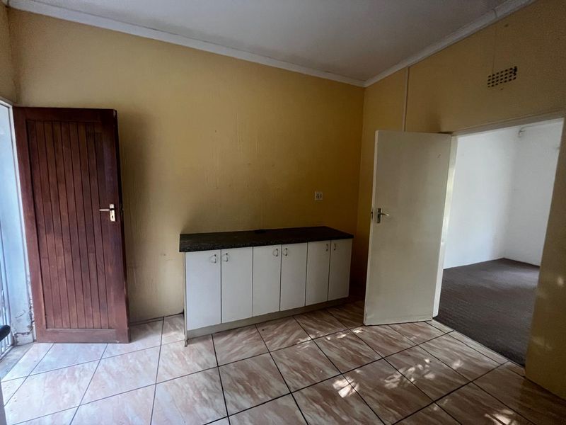 A compact kitchen area featuring base cabinetry with laminate countertops and tiled flooring, offering a functional space ready for updates.