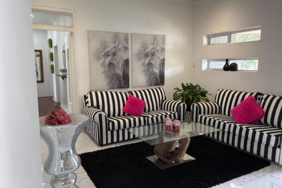 A bright living room featuring white tiled flooring and modern horizontal clerestory windows, providing a clean and neutral foundation for the space.