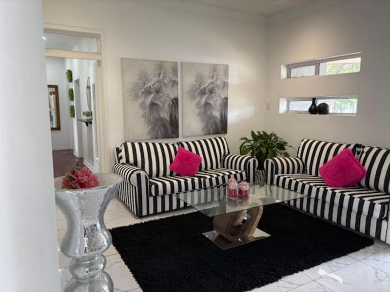 A bright living room featuring white tiled flooring and modern horizontal clerestory windows, providing a clean and neutral foundation for the space.