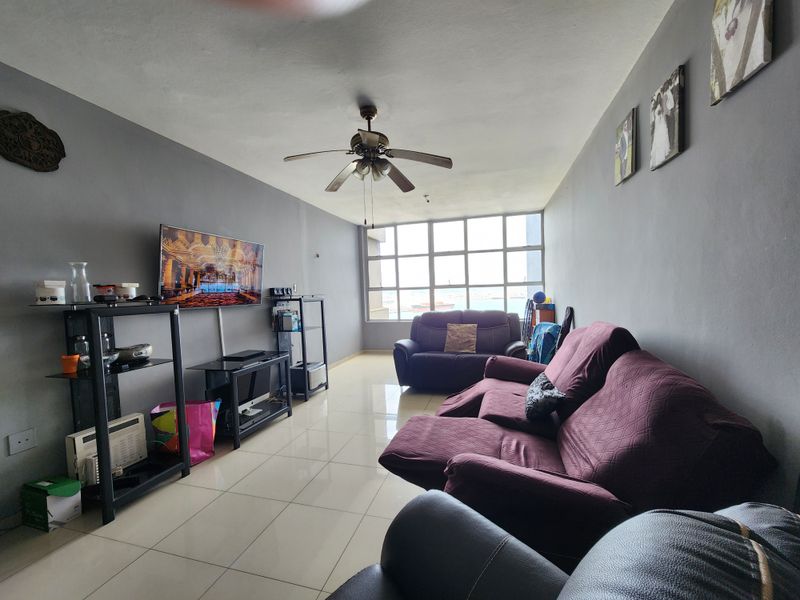 A living room featuring tiled flooring, a ceiling fan, and a large window providing natural light.