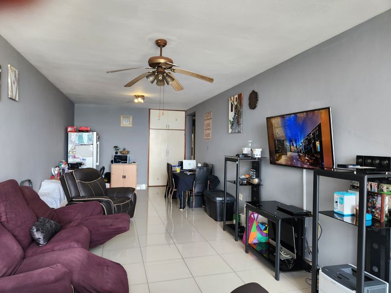 Open-plan living area featuring tiled flooring, a ceiling fan, and built-in storage cupboards, providing a functional and versatile space.