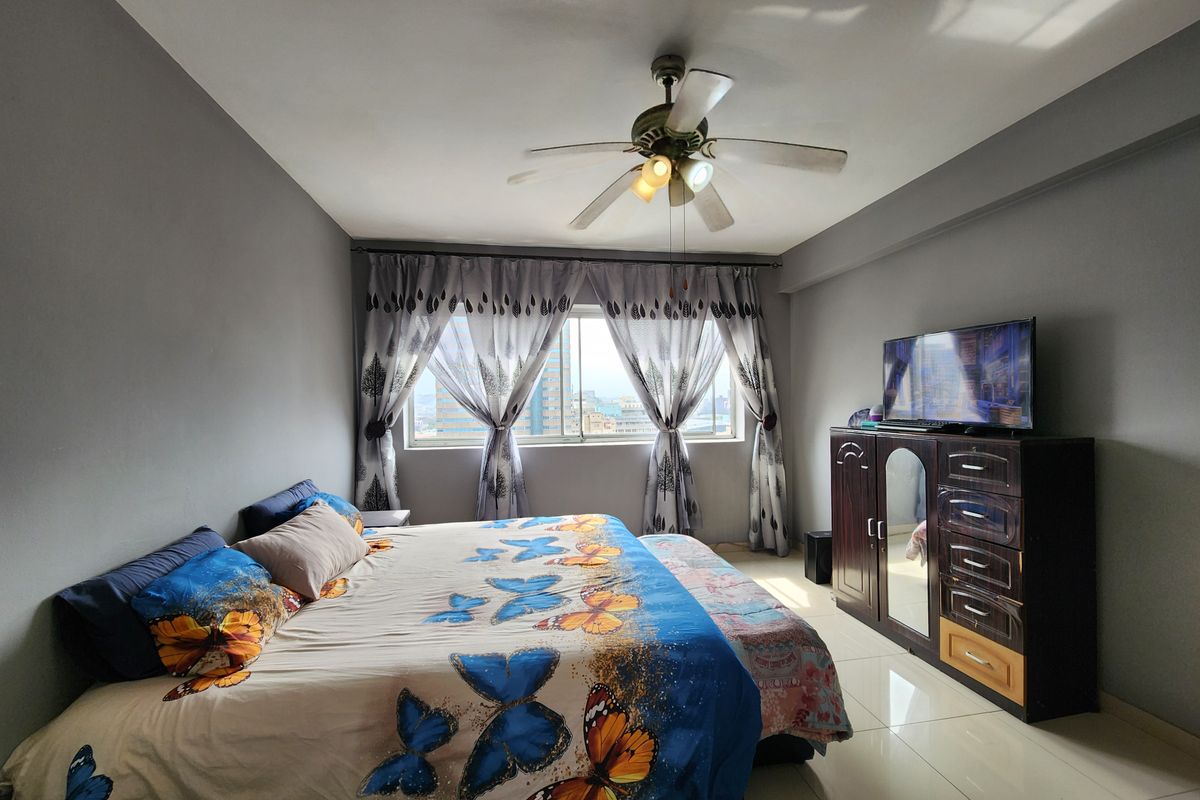 A bedroom featuring tiled flooring and a central ceiling fan, offering a functional space with natural light.