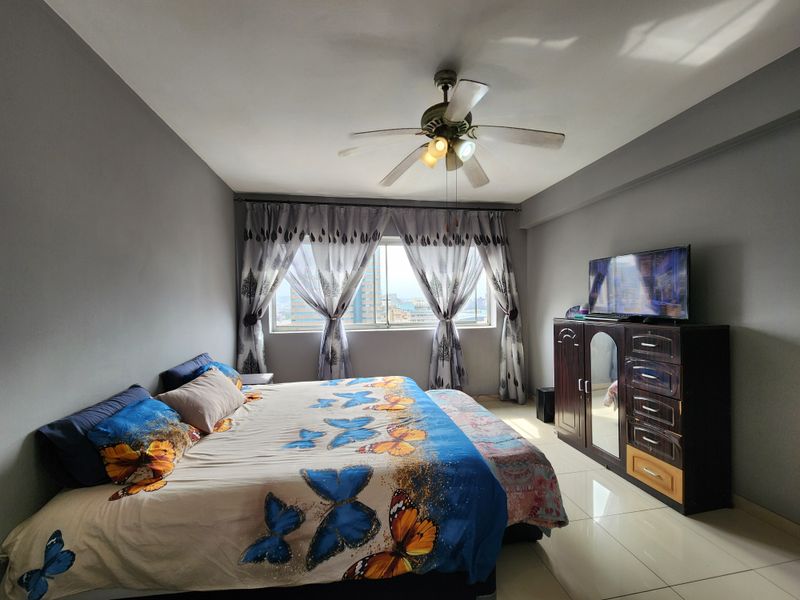 A bedroom featuring tiled flooring and a central ceiling fan, offering a functional space with natural light.