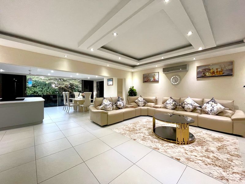 Spacious open-plan living and dining area featuring modern recessed ceiling lighting, neutral tiled flooring, and large sliding doors opening to an outdoor space.