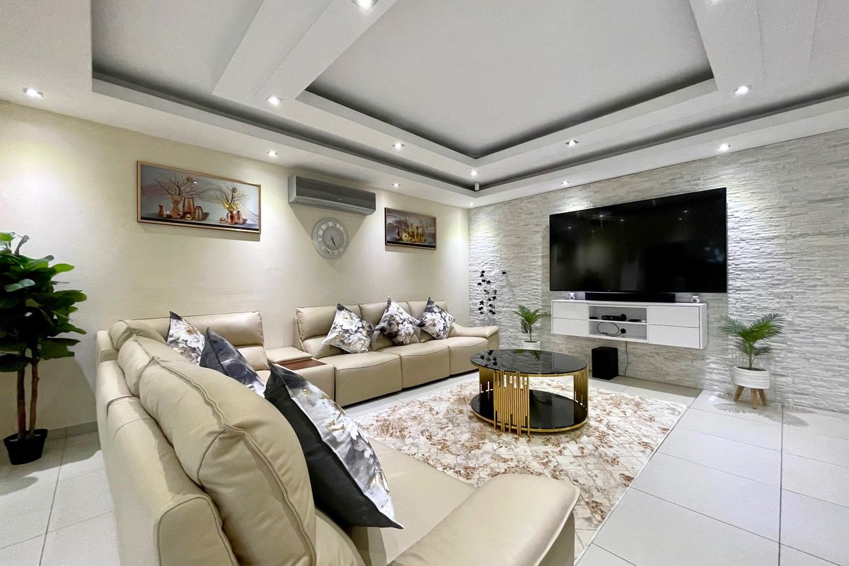 Modern living room featuring a recessed ceiling with downlights, a textured stone feature wall, and a sleek wall-mounted media console.
