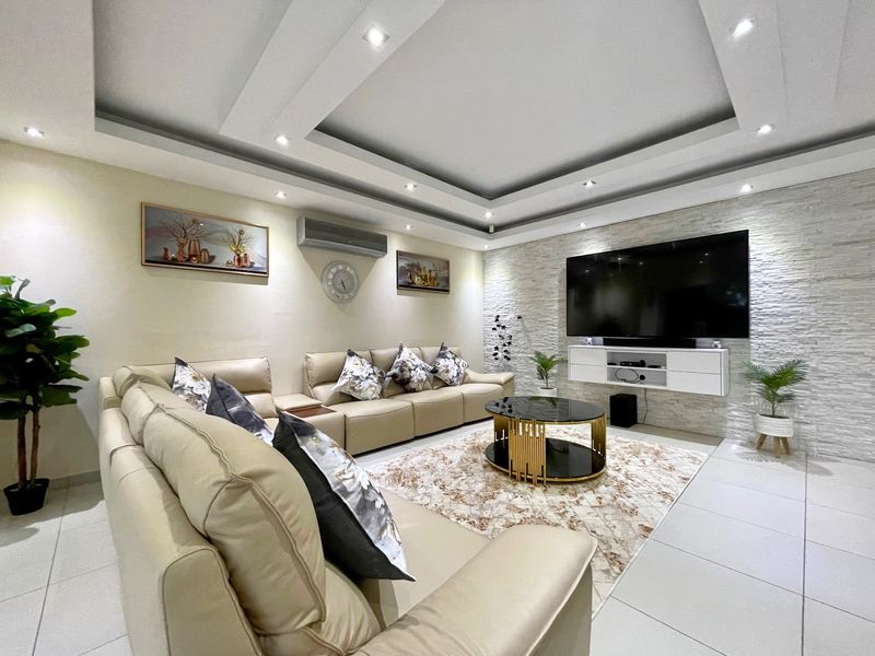 Modern living room featuring a recessed ceiling with downlights, a textured stone feature wall, and a sleek wall-mounted media console.