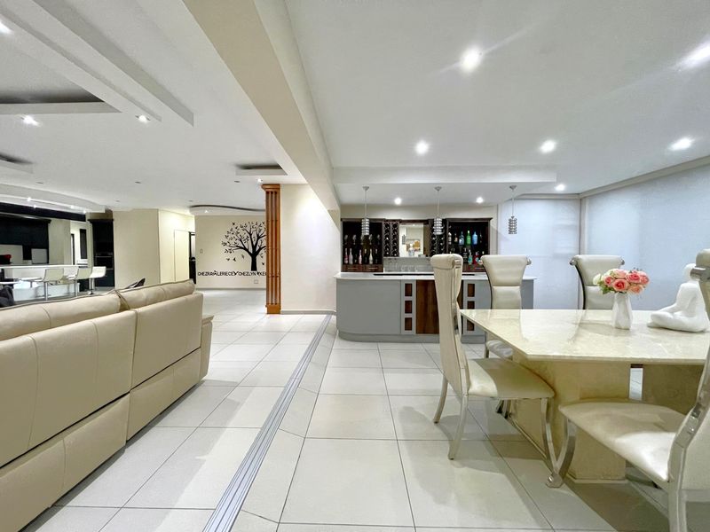 Spacious open-plan living area featuring tiled flooring, recessed ceiling lighting, and a built-in bar, creating a versatile space for entertaining.