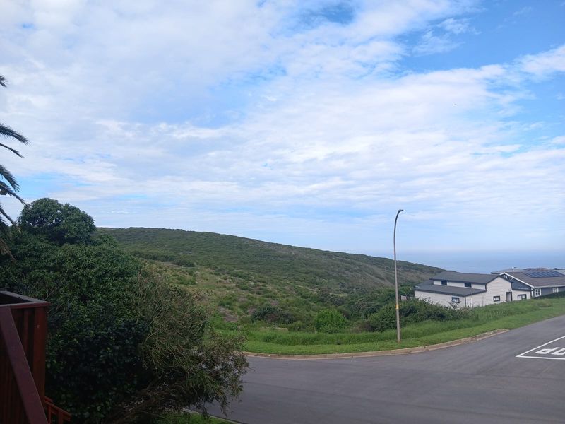 A scenic view overlooking the surrounding landscape, street, and distant coastal horizon from an elevated position.