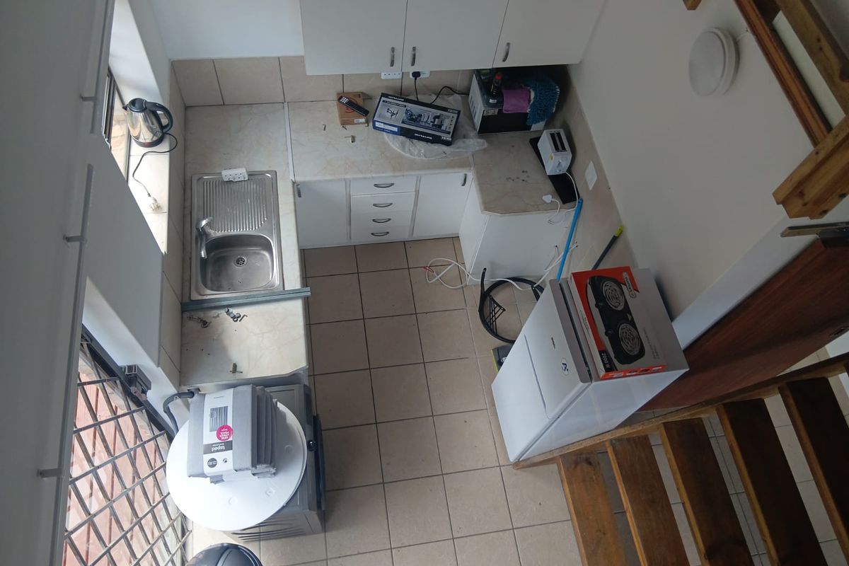 Compact kitchen area featuring tiled flooring, laminate countertops, and built-in cabinetry, viewed from an elevated perspective.