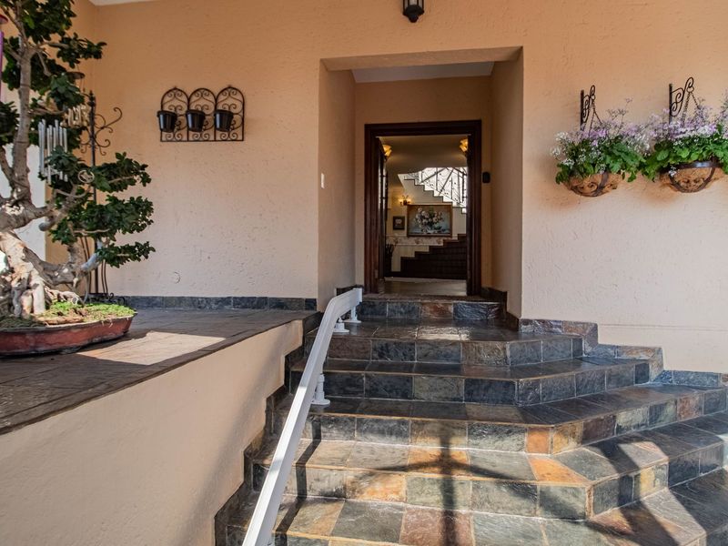 A welcoming front entrance featuring a tiled staircase with a handrail, leading into the home's interior foyer.