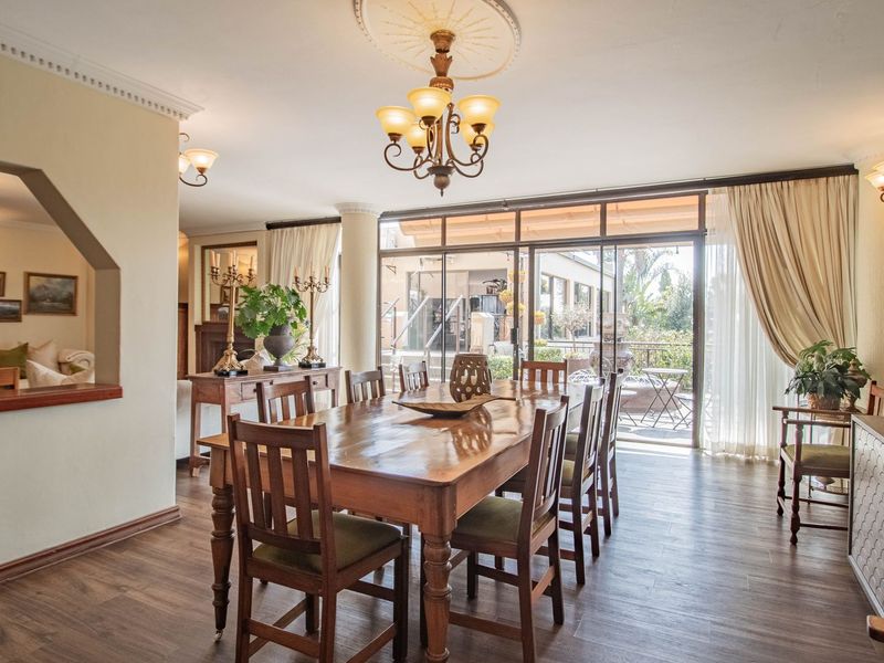Spacious dining room featuring laminate flooring, crown molding, a decorative ceiling rose, and large sliding glass doors providing access to the patio.