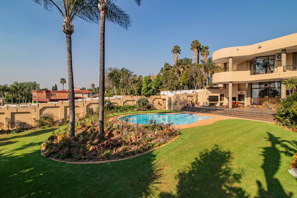 Spacious rear exterior featuring a swimming pool, multi-level patio, landscaped garden, and a multi-story residence with balcony access.