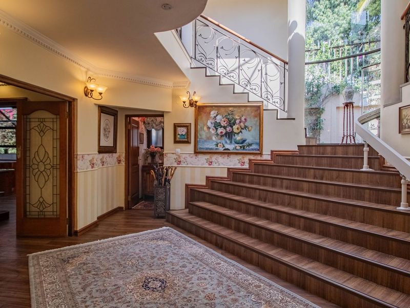 Grand entrance hall featuring a prominent wooden staircase with wrought iron balustrade, decorative wall moldings, and elegant wall sconces.