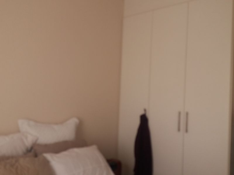 A bedroom featuring a white built-in wardrobe with modern handles.