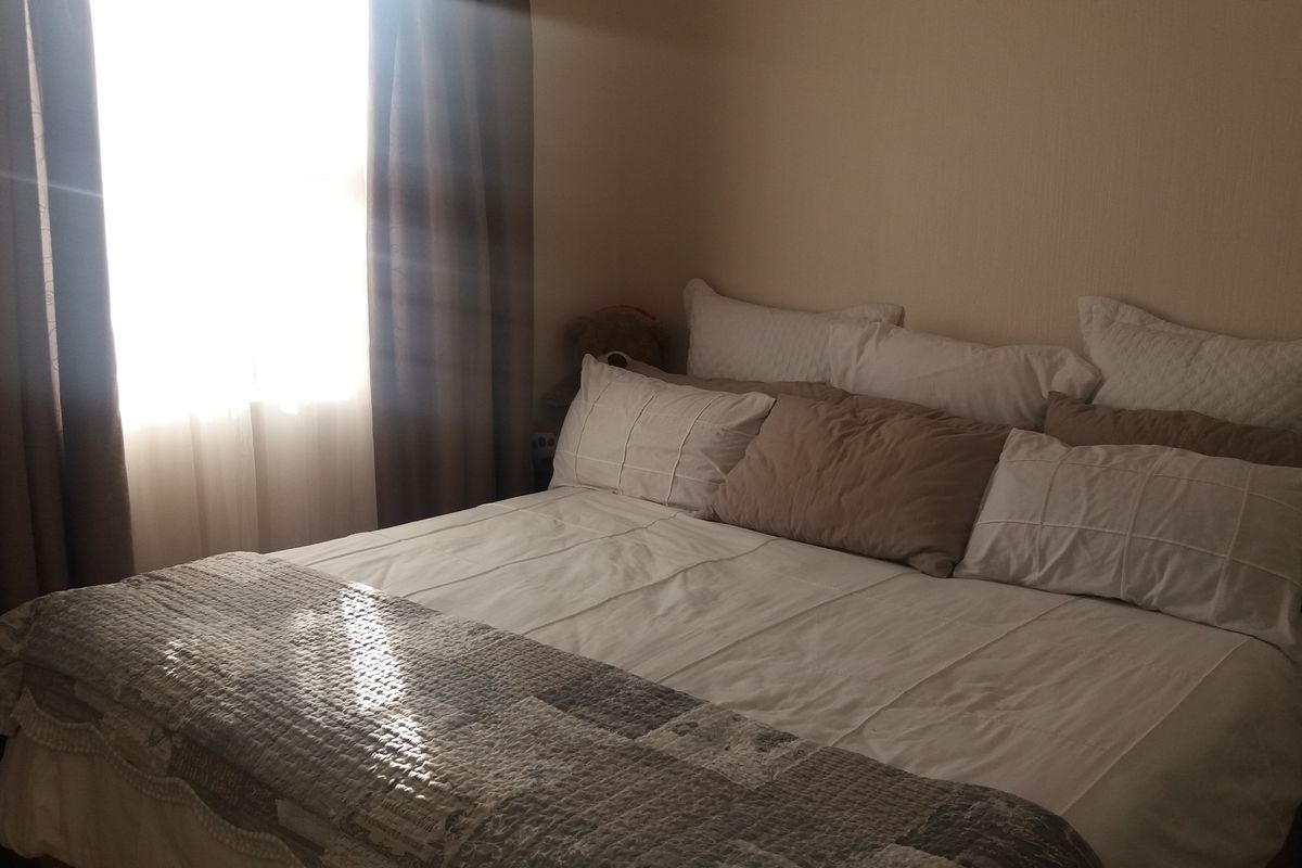 A bedroom featuring natural light from a window with curtains.