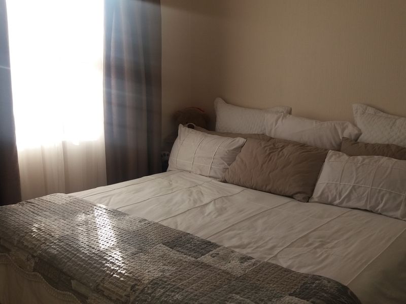A bedroom featuring natural light from a window with curtains.