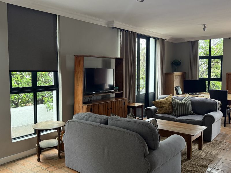 Spacious open-plan living and dining area featuring terracotta tile flooring, large black aluminium windows, and direct access to the outdoor space.